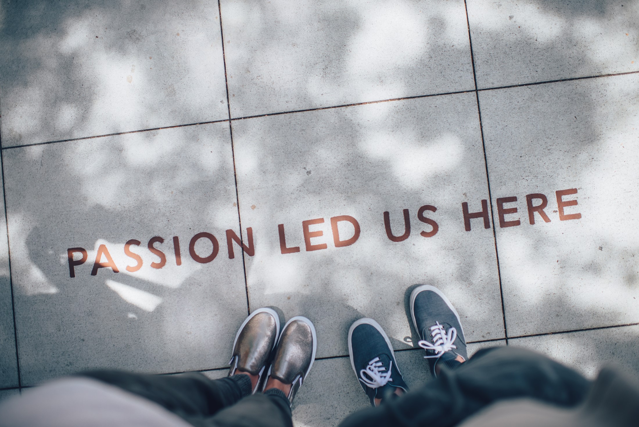 People standing on a sidewalk where Passion Led Us Here is written on the ground